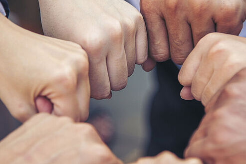 [Translate to English:] Verschiedene Hände zusammen symbolisieren Partnerschaftlichkeit und Gemeinschaft