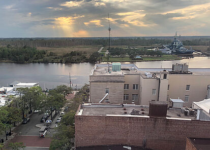 [Translate to English:] Blick auf die Main Street von Wilmington kurz vor Sonnenuntergang. Im Hintergrund der Cape Fear River und das Schlachtschiff North Carolina.